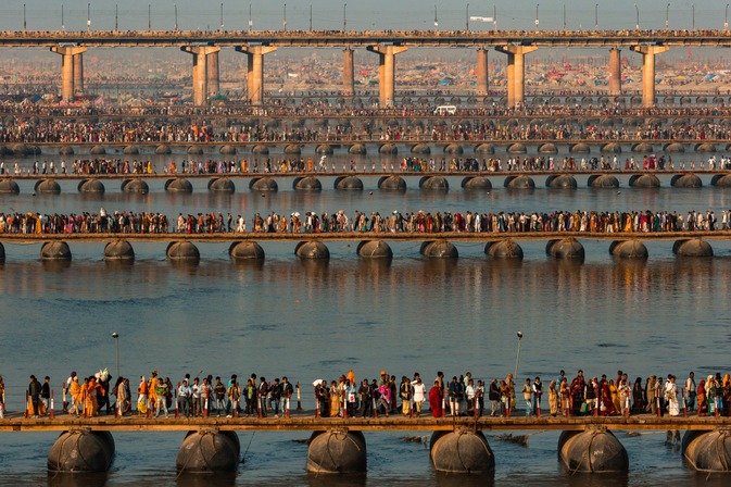 FESTIVAL RELIGIEUX  DE LA KUMBH MELA  SUR LES BORDS DU GANGE, ALLAHABAD, UTTAR PRADESH, INDE (25° 26’ 13,10” N – 81° 53’ 25,62” E). Le pèlerinage religieux de la Kumbh Mela rassemble plusieurs millions de fidèles de l’hindouisme sur les rives du Gange, à la confluence avec la rivière Yamuna. Sa date est déterminée à partir d’un calendrier astral et des positions respectives du Soleil, de la Lune et de Jupiter. Une fois tous les douze ans, il atteint des proportions gigantesques et attire jusqu’à 6 millions de personnes sur une durée de deux mois, comme ce fut le cas d’après certaines estimations en 2013. C’est le plus grand rassemblement humain du monde. Des villes de tentes sortent de terre le long du fleuve et des ponts flottants provisoires sont installés afin d’accueillir les pèlerins durant quarante-cinq jours. Ils viennent se baigner dans le Gange pour se purifier et se laver – eux-mêmes et leur ascendance – de leurs péchés. D’autres religions organisent des pèlerinages pour les croyants en des lieux et à des dates déterminées. Ainsi, près de 5 millions de musulmans se rassemblent chaque année au douzième mois lunaire du calendrier musulman dans la ville de La Mecque, en Arabie Saoudite. Quelque 15 millions de catholiques visitent chaque année le sanctuaire de Notre-Dame de Guadalupe, au Mexique, tandis qu’ils sont environ 6 millions à se rendre au sanctuaire de Lourdes, en France.